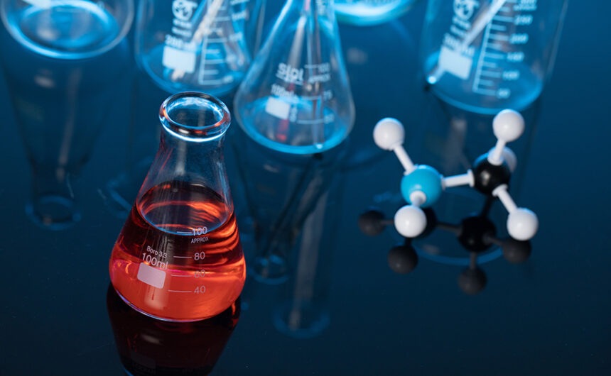 Glass flask with red liquid and a molecule structure on a lab table Ajornament de la normativa de classificació, etiquetatge i envasat de productes químics fins al 2028