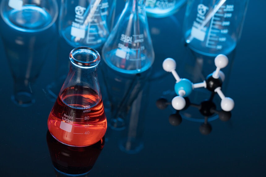Glass flask with red liquid and a molecule structure on a lab table Ajornament de la normativa de classificació, etiquetatge i envasat de productes químics fins al 2028